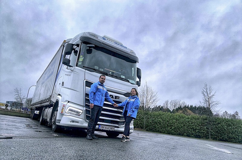 two employees standing in front of a truck